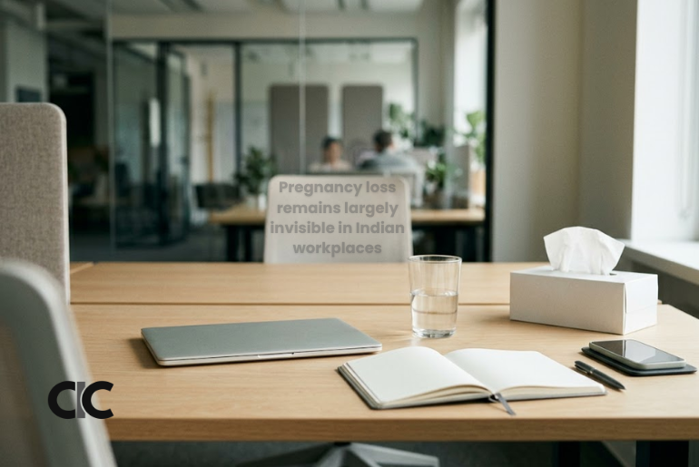 A quiet office desk with a closed laptop, tissue box and notebook, representing pregnancy loss and the need for workplace support. | AI-generated image for representation
