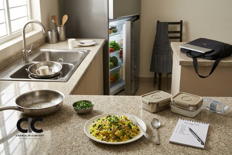 A modern Indian kitchen after breakfast with food, dishes, tiffin boxes, a grocery list and a work bag, showing the unequal division of labour at home.