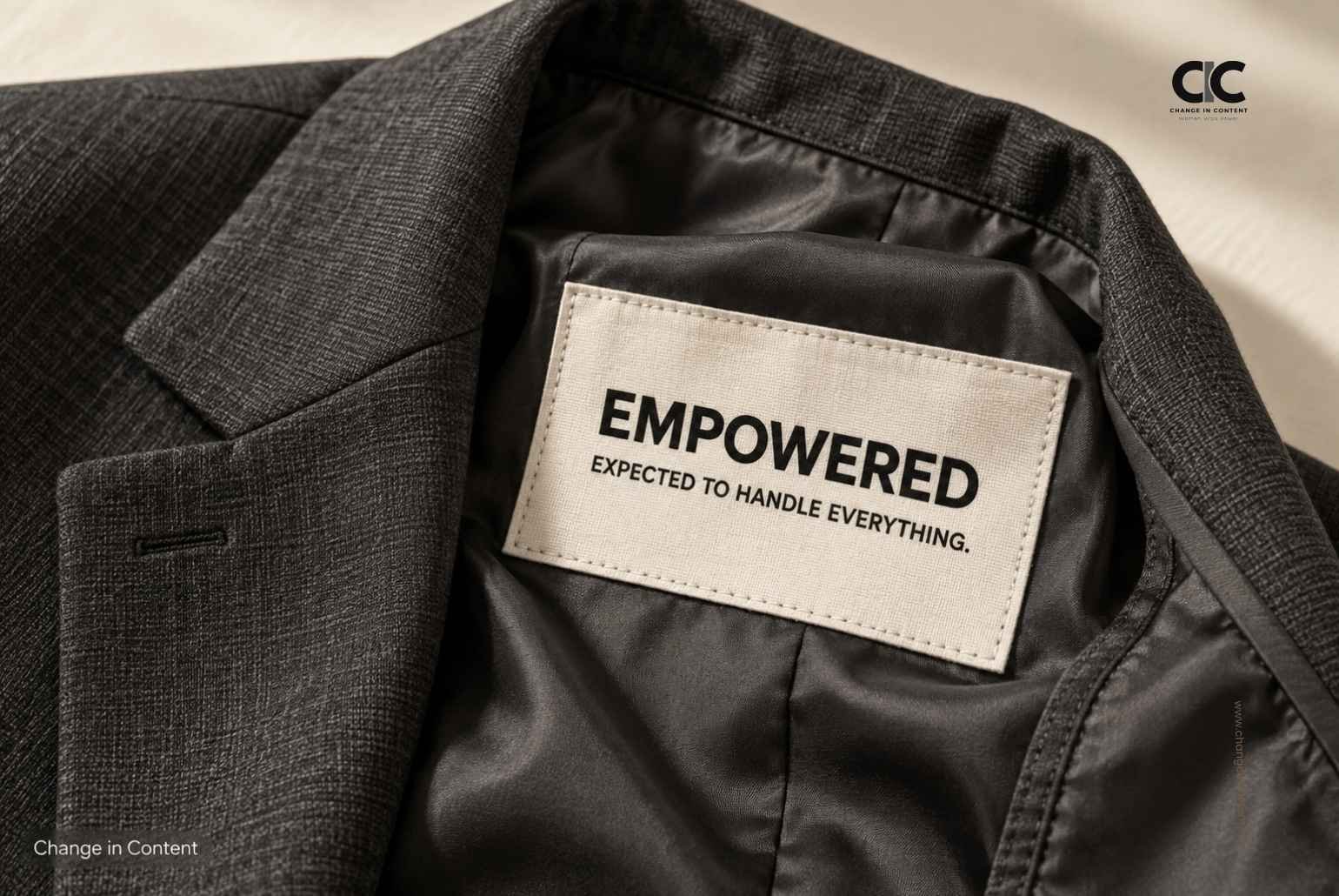 Conceptual blazer label reading “Empowered. Expected to handle everything.”
