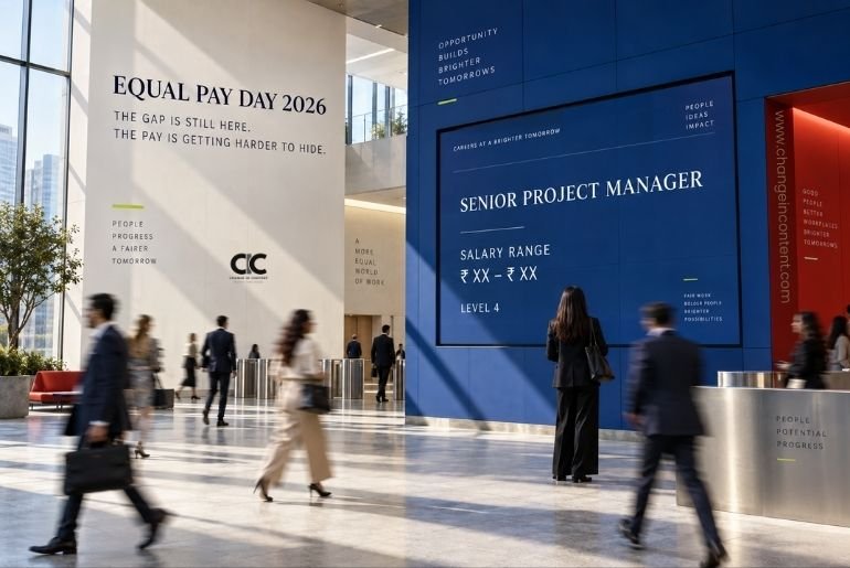Professionals walk through a modern workplace where a job’s salary range is displayed openly, representing the growth of pay transparency on International Equal Pay Day 2026.
